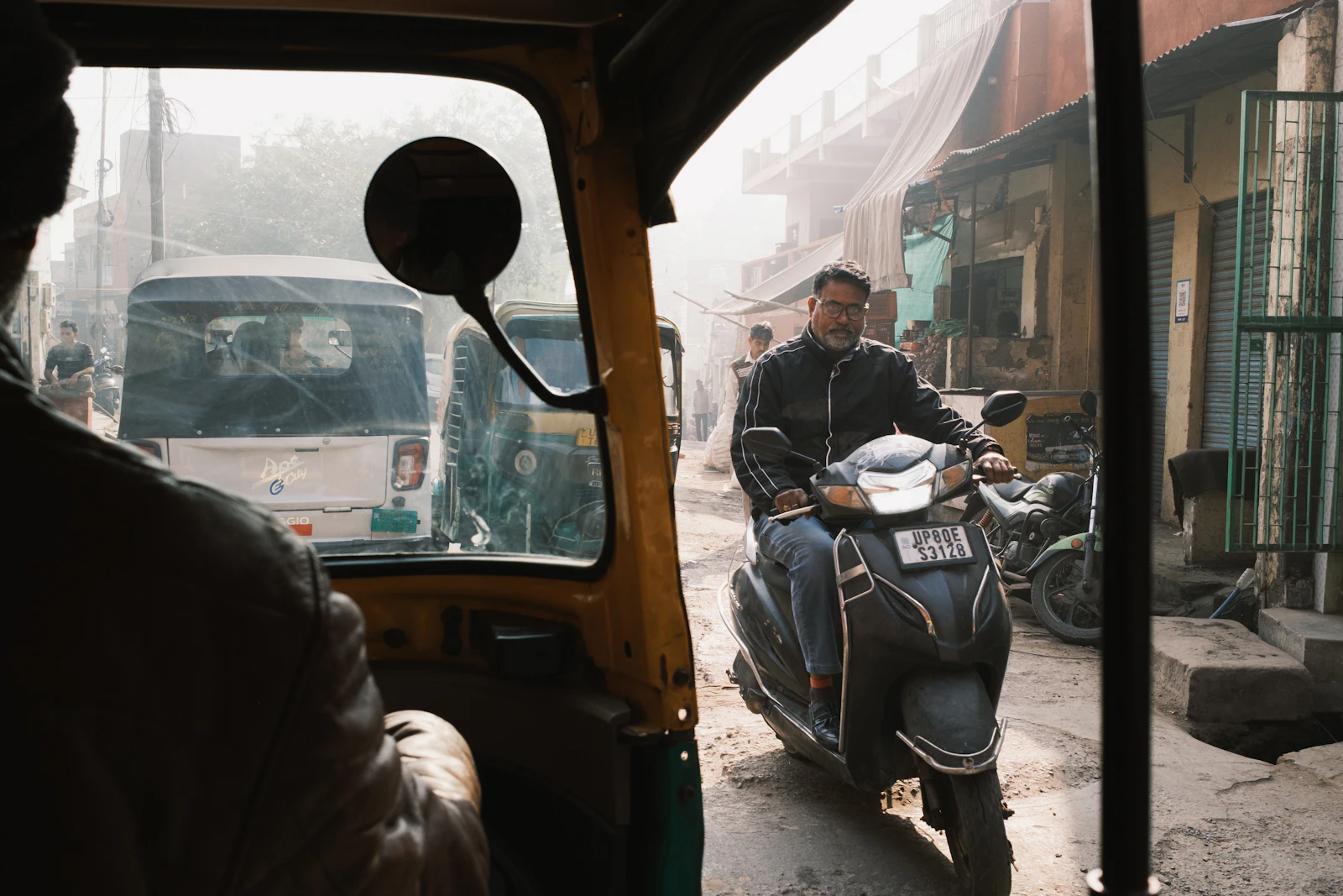 A scooter and rickshaws sharing a narrow street in Agra