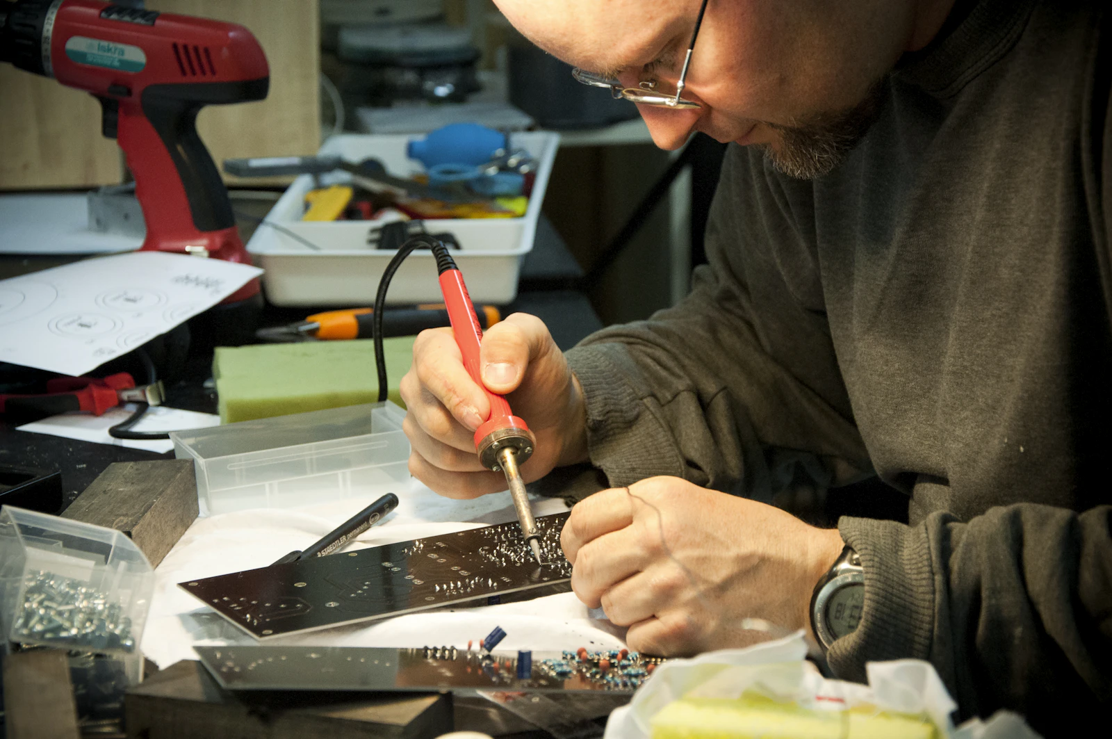 Hands soldering components on an electronics workbench